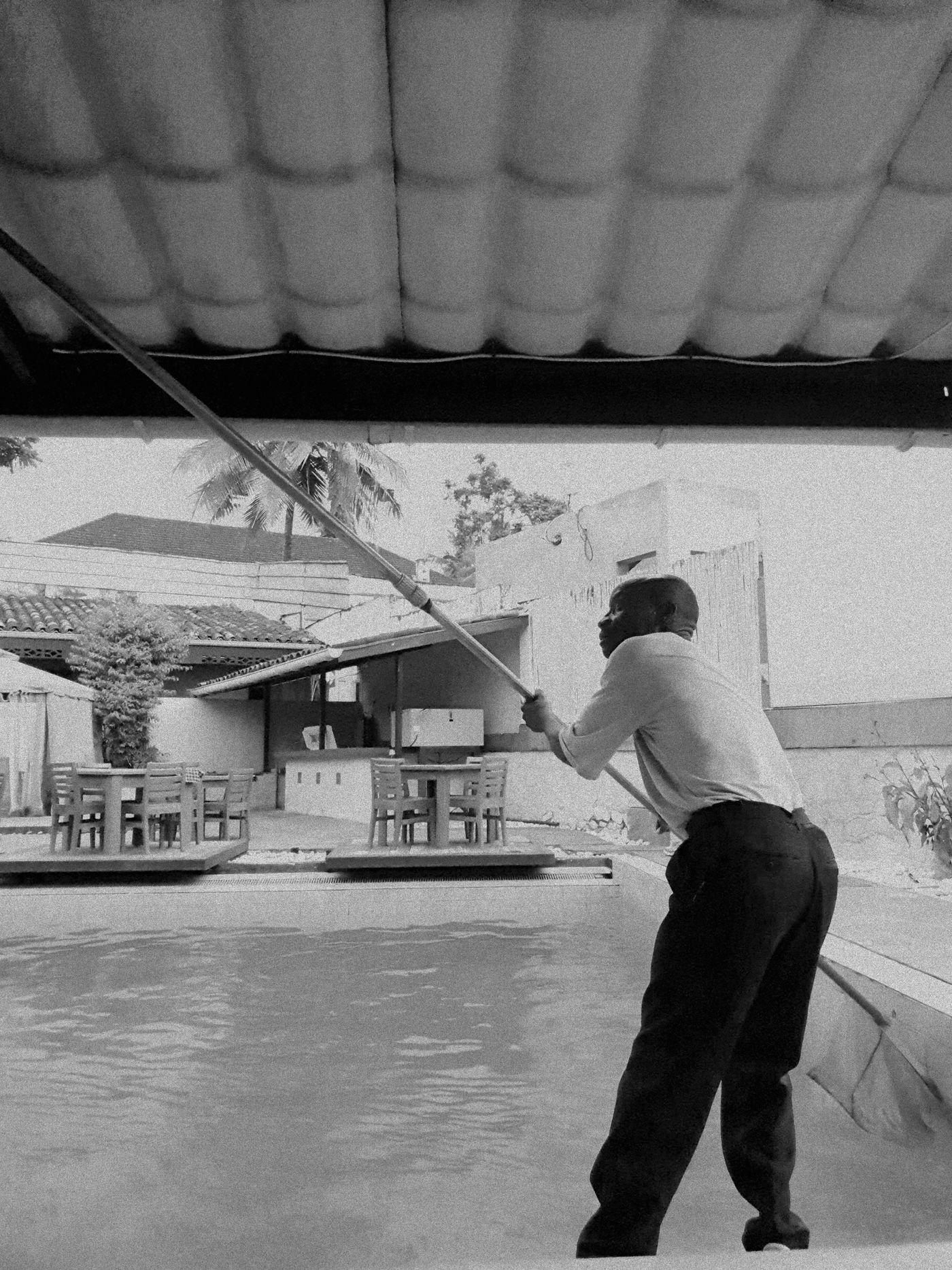 Pool service technician cleaning a pool with a skimmer pole